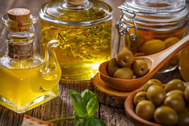Freshly harvested olives berries in wood bowls and pressed oil in glass bottles - Photo, Image