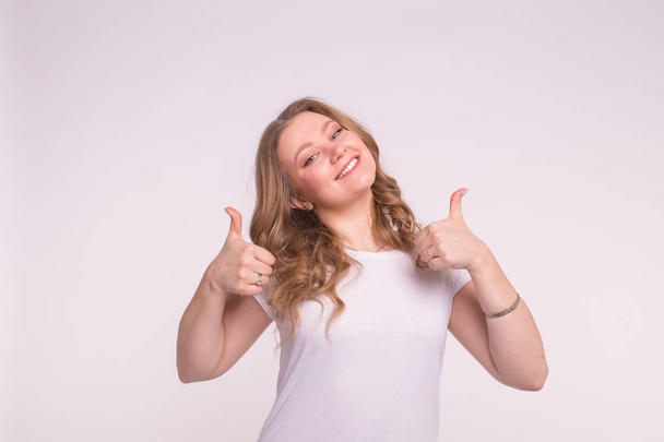 Happy young woman with thumbs up on white background. - Foto, Bild