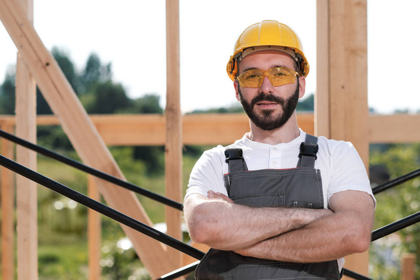 The man is a builder on the roof of a wooden frame house. - Photo, image