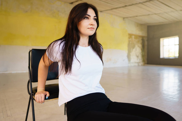 Woman doing physical exercise leaning on chair - Foto, afbeelding