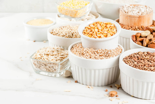 Selection various types cereal grains groats  in different bowl on white marble background, copy space - Foto, afbeelding