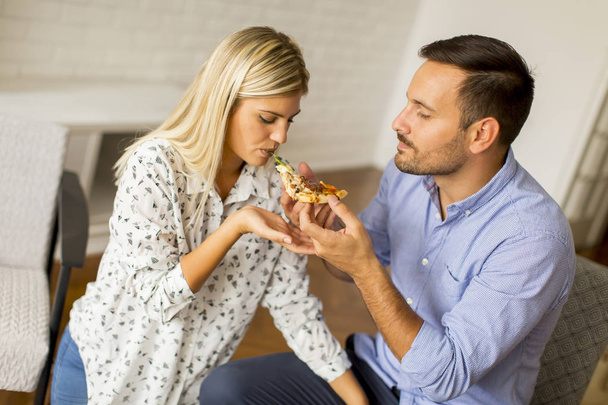Rakastava pari rentouttava kotona ja syö tyylikästä pizzaa
 - Valokuva, kuva