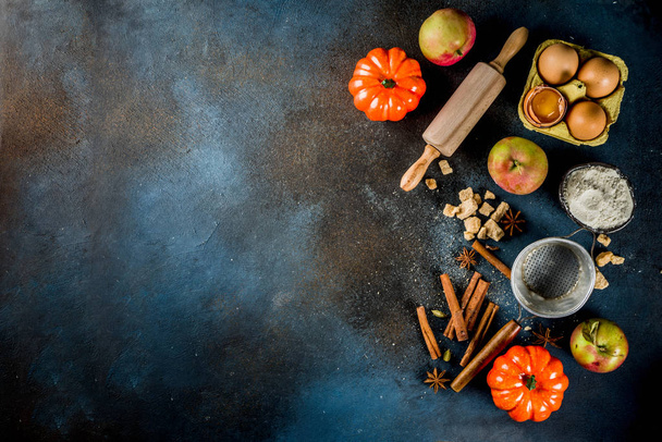Sweet autumn baking concept, cooking background with baking accessories, flour, rolling pin, decorative pumpkins, apples, cinnamon spices with anise cardamom sugar. Dark blue rusty background top view copy space - Фото, зображення