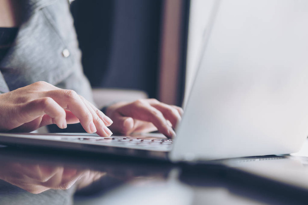 Immagine ravvicinata delle mani di una donna d'affari che lavora e digita sulla tastiera del computer portatile su un tavolo di vetro - Foto, immagini