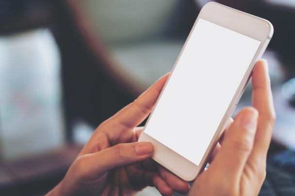 Maketa obraz ruky držící mobilní telefon s prázdná bílá obrazovka v retro kavárně - Fotografie, Obrázek