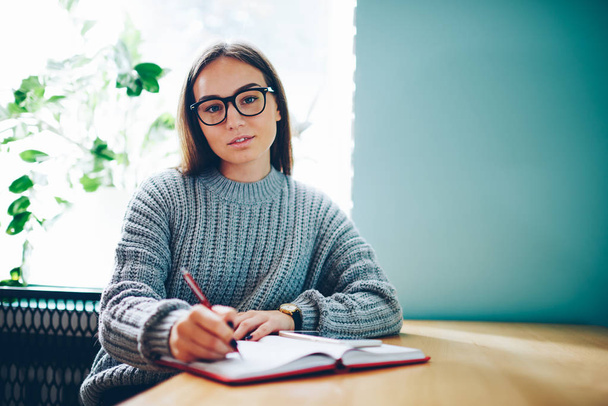 Half length portrait of skilled student in stylish eyeglasses working on new training project sitting at notebook for notes in university interior.Copy space area for advertising text message - Фото, зображення