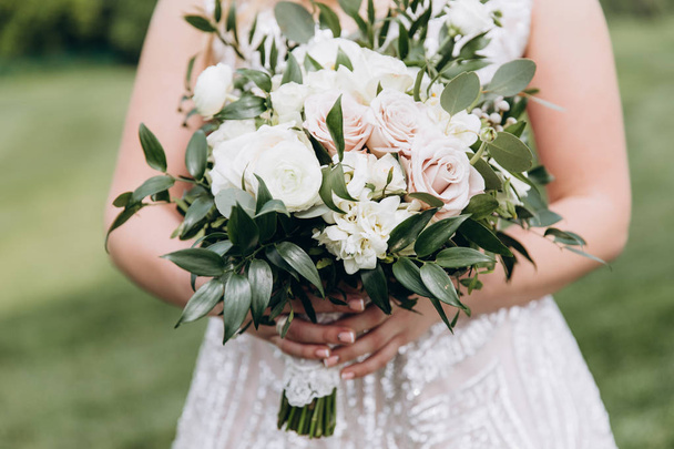 Bride in white wedding dress with a beautiful bouquet of roses. - Foto, Bild