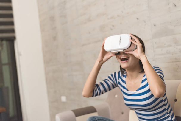 Азиатская женщина использует VR-гарнитуру дома
 - Фото, изображение