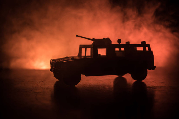 Wojskowy samochód patrol na ciemnym stonowanych mglisty tło. Koncepcja wojny armia. Sylwetka pojazdu pancernego z pistoletu w akcji. Urządzone. Selektywny fokus - Zdjęcie, obraz