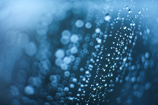 Gotas de lluvia sobre el vaso con bokeh desenfocado. Fondo dramático azul
 - Foto, Imagen