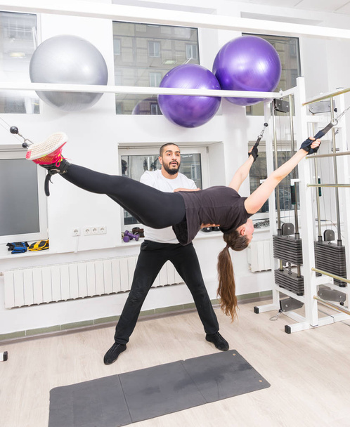 Dopasuj kobieta ćwiczenia z taśmy do zawieszania pod nadzorem instruktora profesjonalny fitness w siłowni - Zdjęcie, obraz