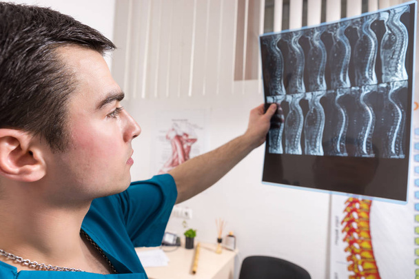 Radiologist studying X-ray image of human spine in consulting room - Foto, afbeelding