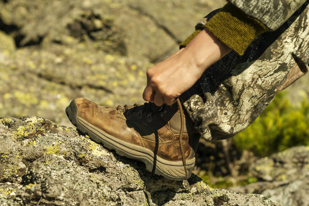 manos atando cordones de zapatos en una bota de senderismo desgastada de cerca
 - Foto, imagen
