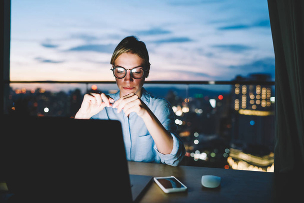 Serious female freelancer puzzled on solution working distantly at home desktop late at evening, concentrated on idea for startup business woman using laptop computer for networking overworking - Fotó, kép