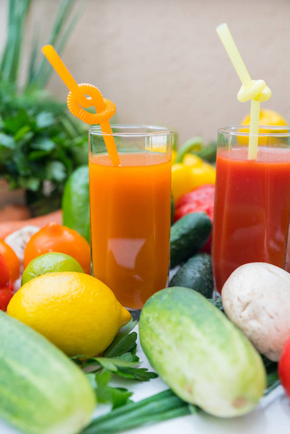 Auswahl an frischen Obst- und Gemüsezutaten mit zwei gesunden Smoothies, serviert in hohen Gläsern mit Strohhalmen, aus nächster Nähe. - Foto, Bild