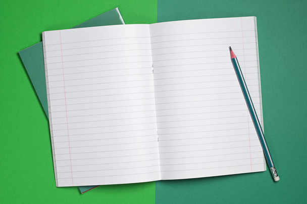 Taccuino e matita aperti su sfondo verde, vista dall'alto
 - Foto, immagini
