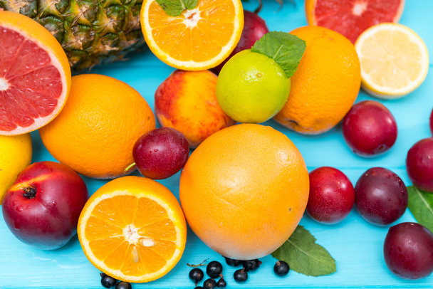 Selectie van verse, gezonde tropisch fruit op blauw hout met een verscheidenheid van citrus en bosbessen, nectarine, pruimen, ananas - Foto, afbeelding