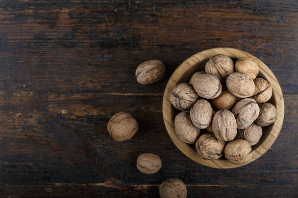 whole walnuts in a plate on an old country table and against a dark background. place for tex - Photo, image
