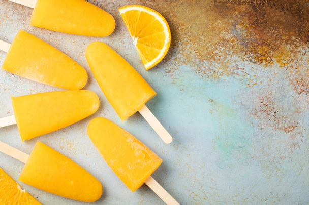 Ghiaccioli arancioni con succo su un bacino blu. Ice pops, posizione piatta, vista dall'alto con spazio di copia
. - Foto, immagini
