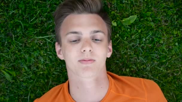 Portret chłopca nastolatek odpoczynek na trawie marzy, myśląc z bliska - Materiał filmowy, wideo
