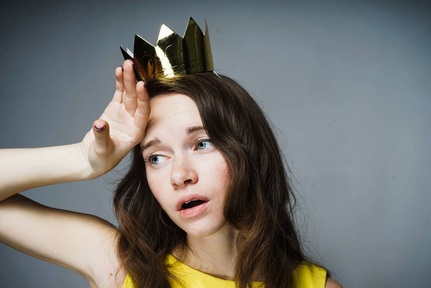 sad tired blue-eyed girl posing, wearing a golden crown - Photo, Image