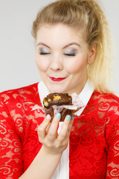 Sweet food sugar make us happy. Attractive blonde woman holds yummy chocolate cupcake in hand. - Фото, зображення
