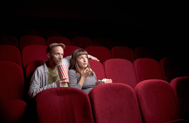Young couple sitting at red movie theatre - 写真・画像