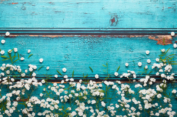 Состав белых цветов на голубом винтажном деревянном фоне с копировальным пространством. Плоский стиль, вид сверху, минимальный стиль
. - Фото, изображение