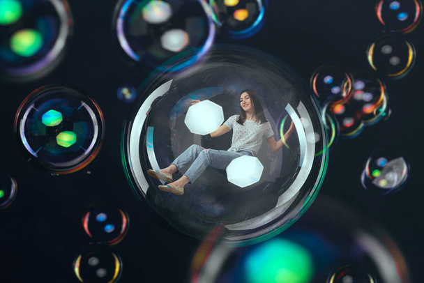 Cute woman flying in big soap bubble, happy fantasy. Female person blowing colorful balloons - Foto, Bild