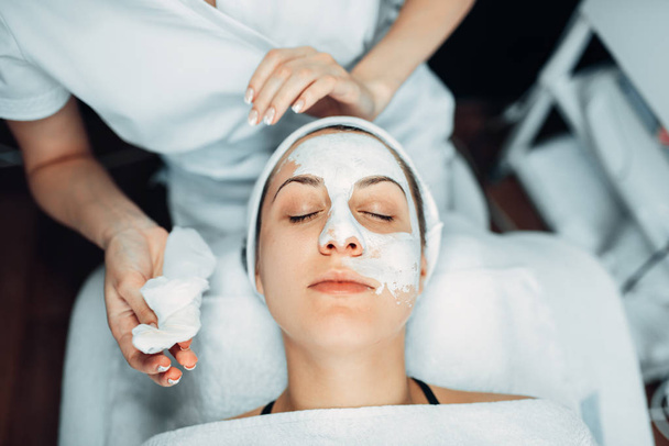 Beautician hands with cream against patient face rejuvenation cosmetic, cosmetology clinic. Facial skincare in spa salon, health care - Photo, Image