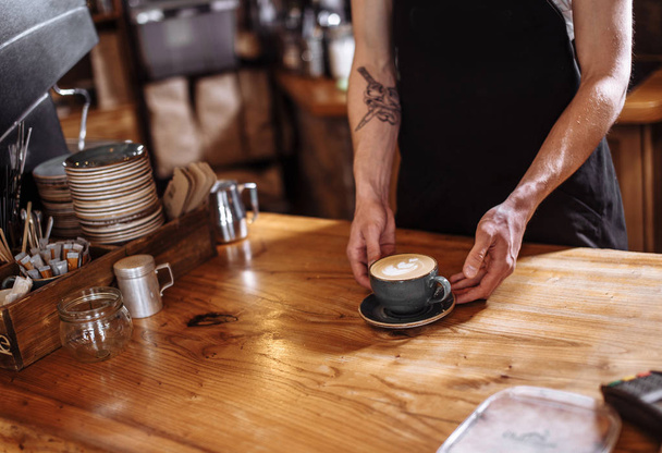 a man is serving latte on a wooden table - Photo, Image