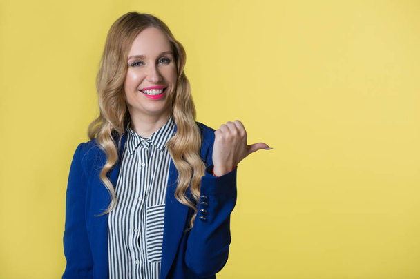 beautiful young woman with flowing hair in a blue jacket on a yellow background - Foto, Imagen