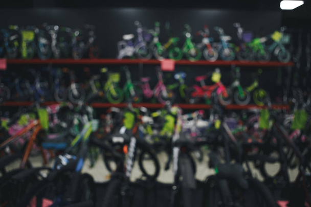 Размытое изображение нескольких рядов детских велосипедов, висящих на стойке в универмаге Хамбл, штат Техас, США. Различные яркие велосипеды цвета для ребенка в магазине велосипедов. Активный образ жизни, винтажный тон
 - Фото, изображение