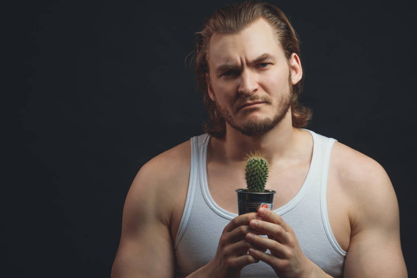 Bearded sporty botanic holding a cactus in hands. sportsman like plants - Фото, изображение