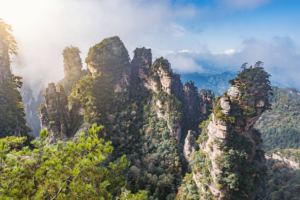 Sun breaks through the clouds above the colorful cliffs in Zhangjiajie Forest Park. China. - Foto, imagen