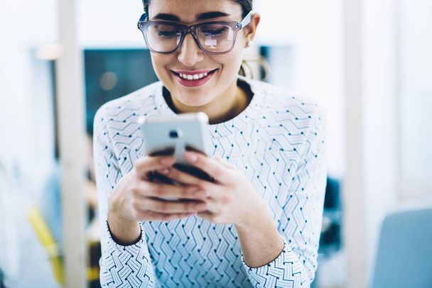 Cropped image of prosperous businesswoman in eyewear getting good news on email typing message for feedback,successful female happy about getting discount for mobile service holding telephone - Foto, afbeelding