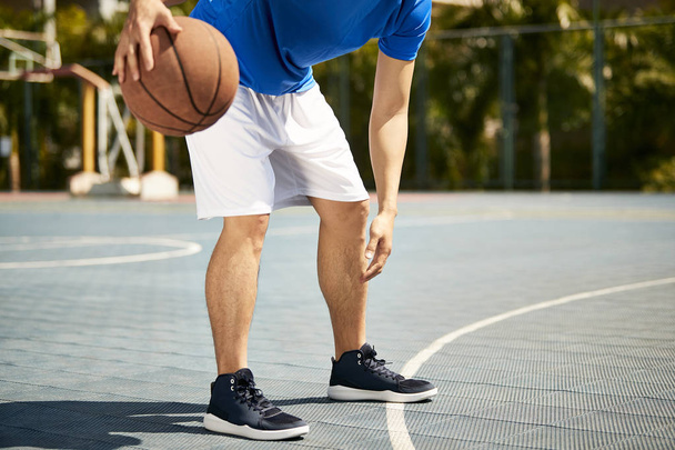 jonge Aziatische mannelijke basketballer dribbelen en het beoefenen van bal behandeling vaardigheid op Hof. - Foto, afbeelding
