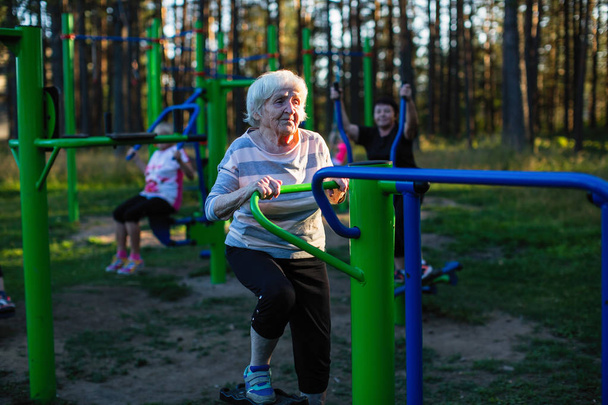 Una anciana está haciendo ejercicios en el parque deportivo
. - Foto, Imagen