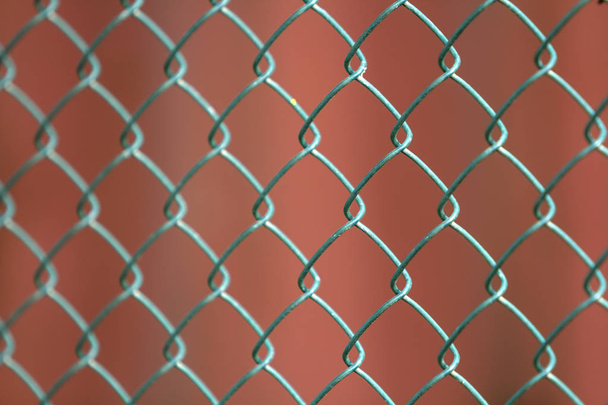 Крупный план изолированного окрашенного простого геометрического черного железа металлической цепи звена цепи ограждения на темно-красном фоне. Концепция ограждения, защиты и ограждения
. - Фото, изображение