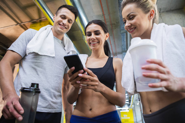 Cheerful sporty mates are using smartphone in gym - Φωτογραφία, εικόνα