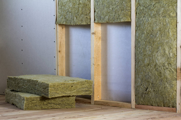 Holzrahmen für zukünftige Wände mit Trockenbauplatten isoliert mit Steinwolle und Fiberglas-Isolierung Personal für kalte Barriere. Komfortables, warmes Zuhause, Wirtschaftlichkeit, Bau- und Sanierungskonzept. - Foto, Bild