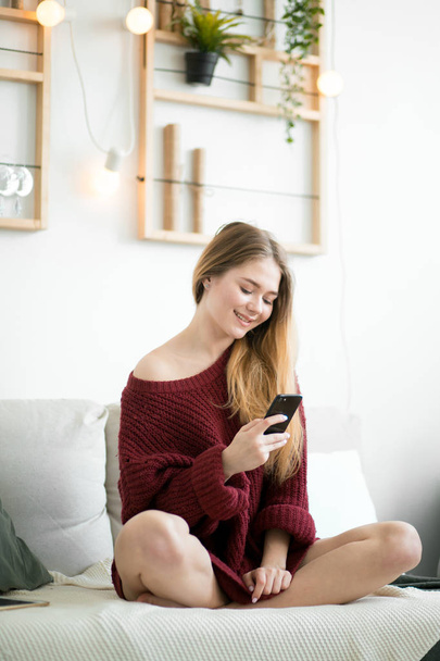 a pleasant female student browsing the Net on the sofa indoors - Foto, Bild