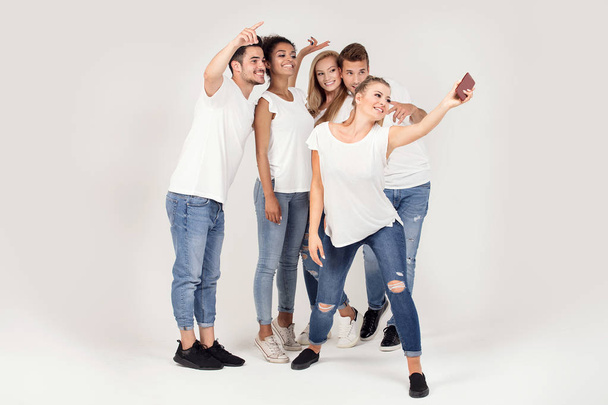 Groupe de jeunes apprécient leur compagnie, souriant, s'amusant ensemble, prenant selfie par téléphone portable
. - Photo, image