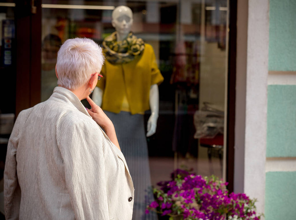 close up back view photo of pensive woman standing in front of the shop - Foto, imagen