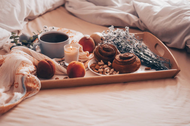 Frühstück im Bett, ein Tablett Tee, Croissants, Obst, Blumen. Morgen. gemütliche Wohnung. Romantik. helles Hintergrundlayout. Ein freier Tag - Foto, Bild