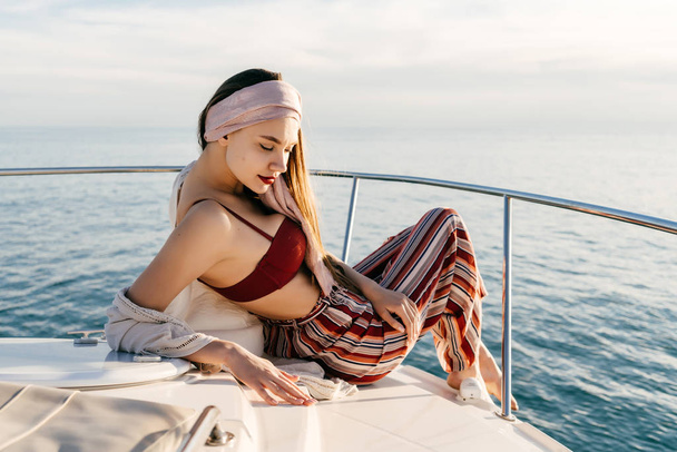 stylish young girl in fashionable pants is resting and relaxing on her yacht, sailing on the sea - Foto, Bild