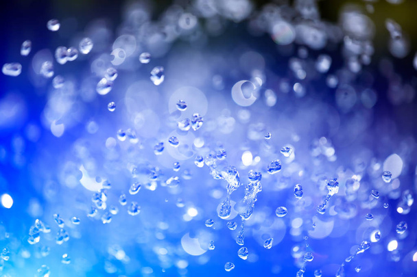 Zbliżenie kropel wody na niebieskim tle gradientowym, pokryte kroplami kondensacji wody. Zbliżenie kropli fontanny wznoszącej się w górę - Zdjęcie, obraz