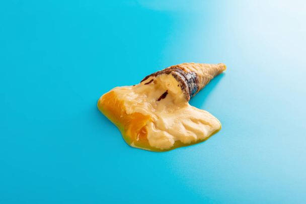 mini mango or orange flavor ice cream cone melting on blue background - Photo, Image