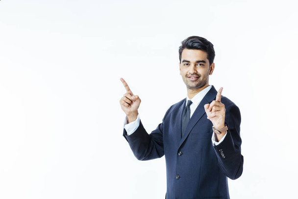 Portrait d'un bel homme souriant en costume d'affaires et cravate pointant vers le haut avec les deux doigts, isolé sur fond de studio blanc
 - Photo, image