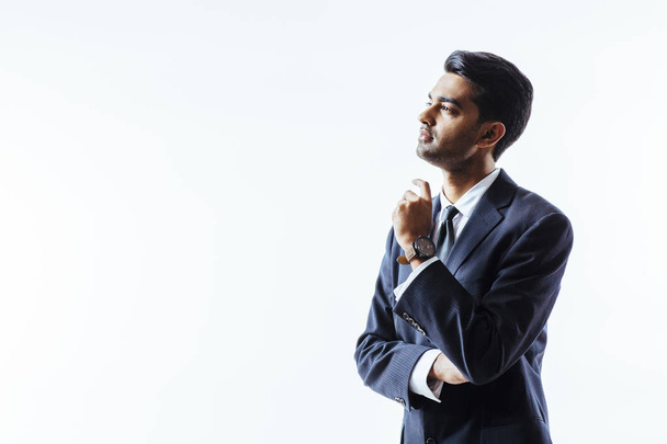 Hombre interesado en traje de negocios mirando hacia arriba con un brazo cruzado y otro levantado, aislado en blanco
 - Foto, Imagen